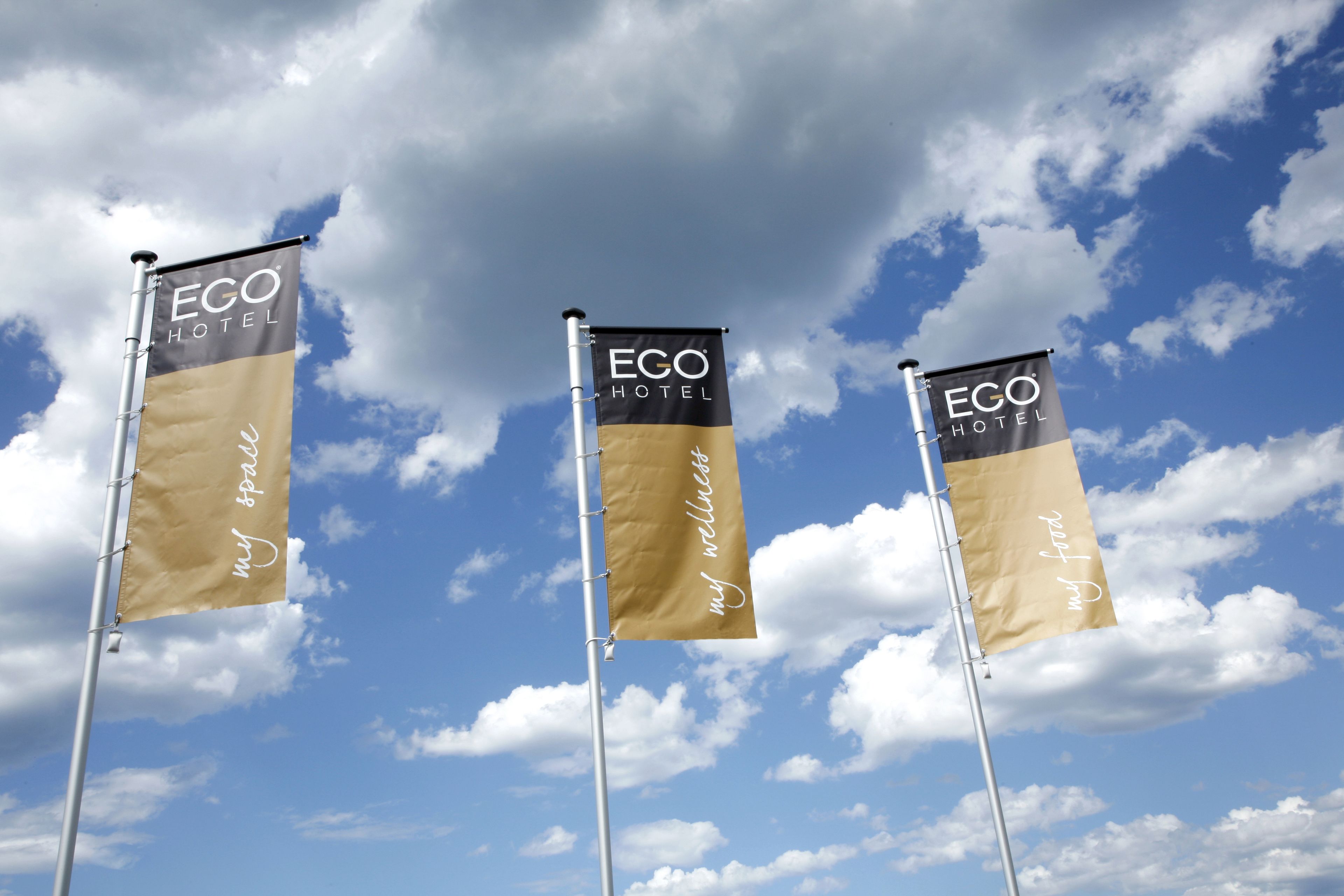 Three ECO HOTEL flags against a partly cloudy sky.