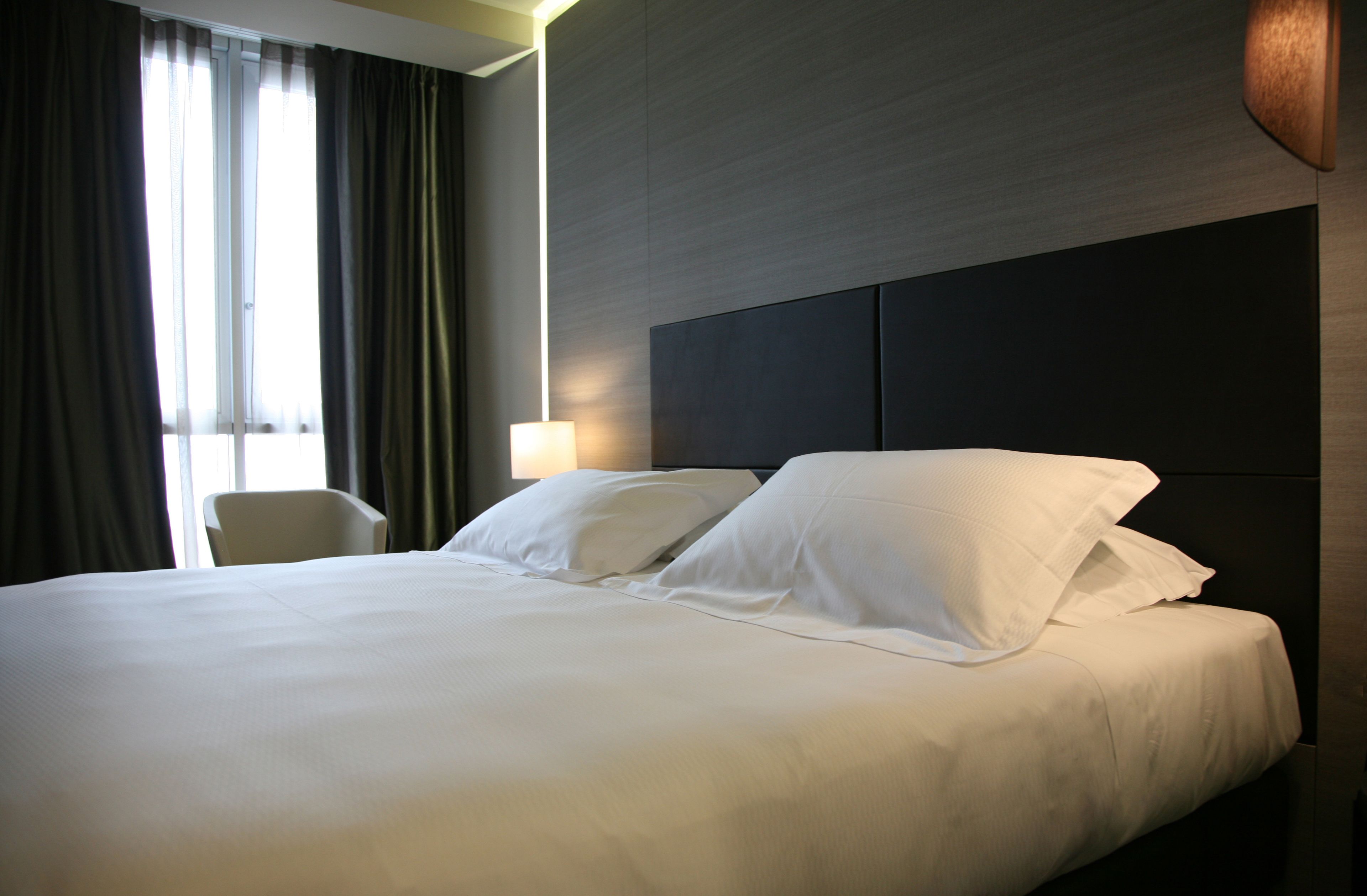 Une chambre d’hôtel avec un grand lit, une chaise et une lampe.