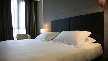Une chambre d’hôtel avec un grand lit, une chaise et une lampe.