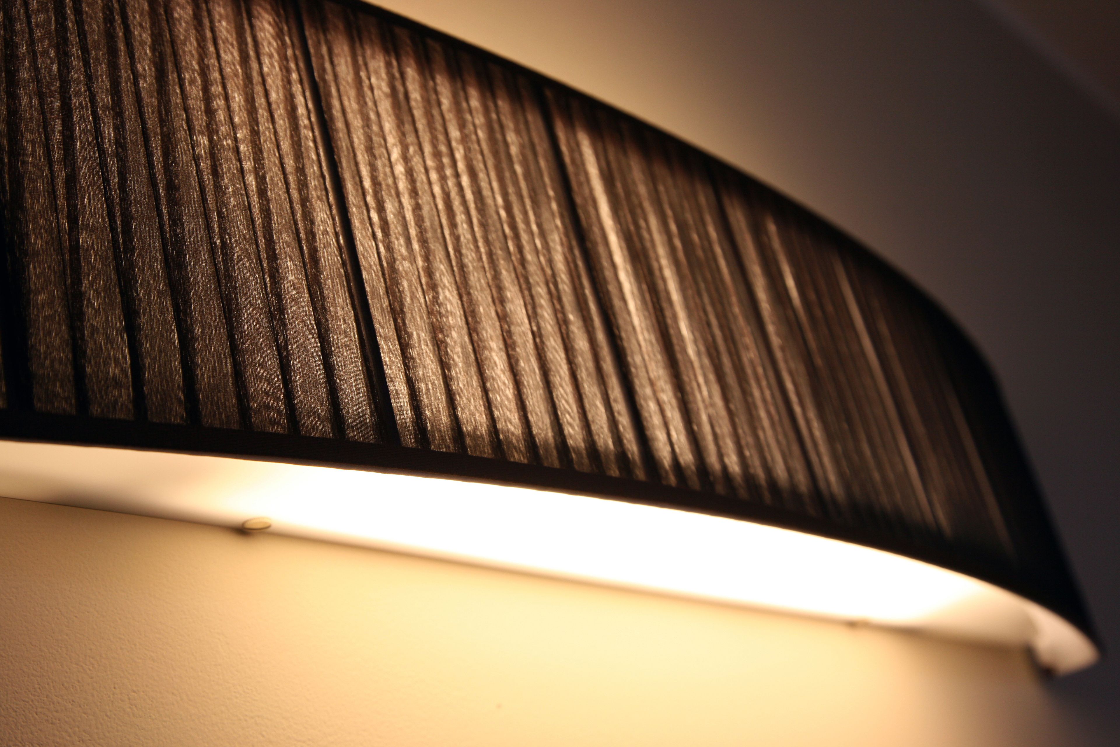 A close-up of a wall with a textured, dark-colored panel and a white baseboard.