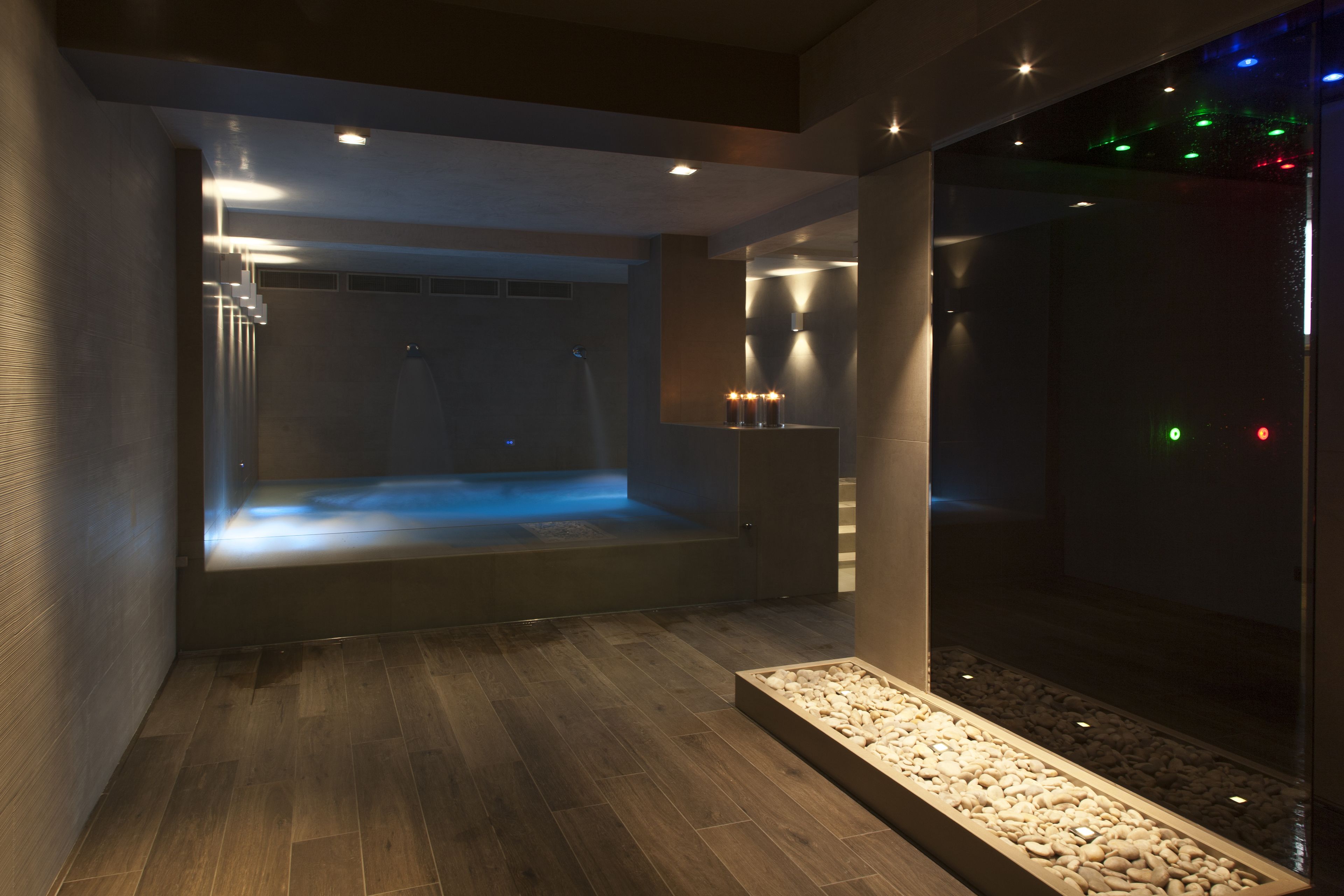 A modern spa room with a heated floor, a glass enclosure, and ambient lighting.