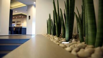 Un área de recepción con una larga barra, piedras y altas plantas verdes.