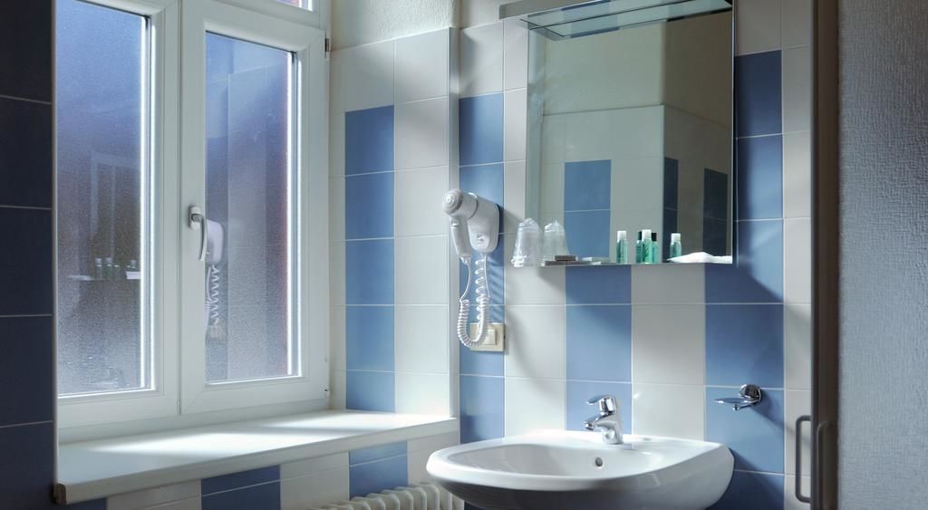 A bathroom with a window, a sink, a mirror, and a towel rack.
