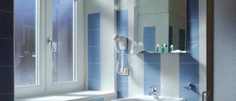 A bathroom with a window, a sink, a mirror, and a towel rack.