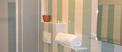 A bathroom with green and white tiles, a shower, a towel rack, and a soap dish.
