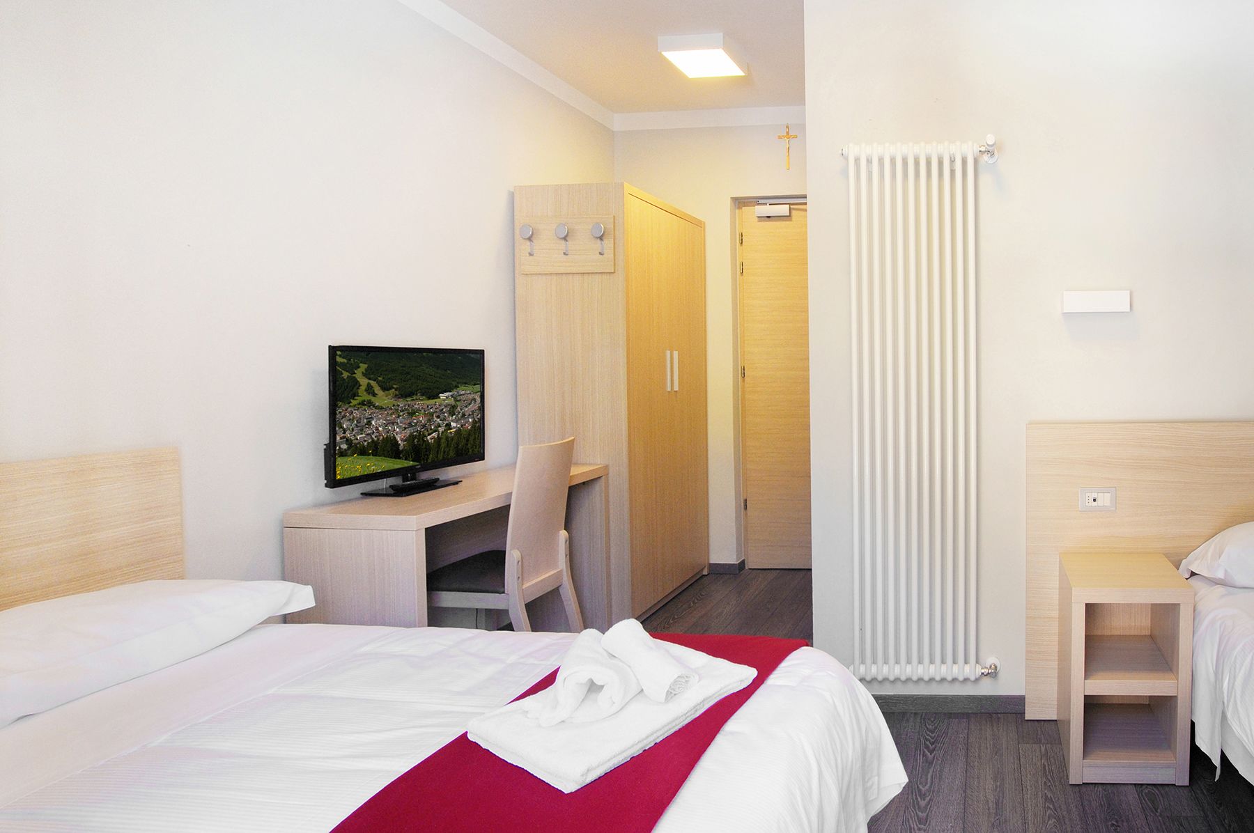 Une chambre d’hôtel équipée d’un lit, d’un bureau avec un ordinateur, d’une télévision, d’une armoire et d’un radiateur.
