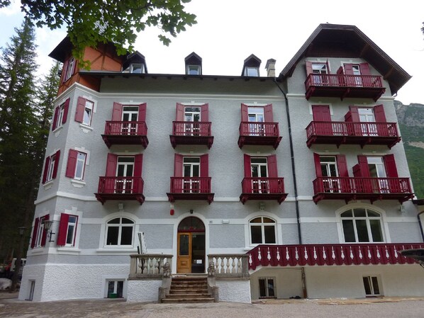 Un edificio de varios pisos con balcones rojos y una entrada central.