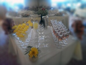 Uma mesa com diversos copos, alguns com rodelas de laranja, e um pequeno arranjo floral.