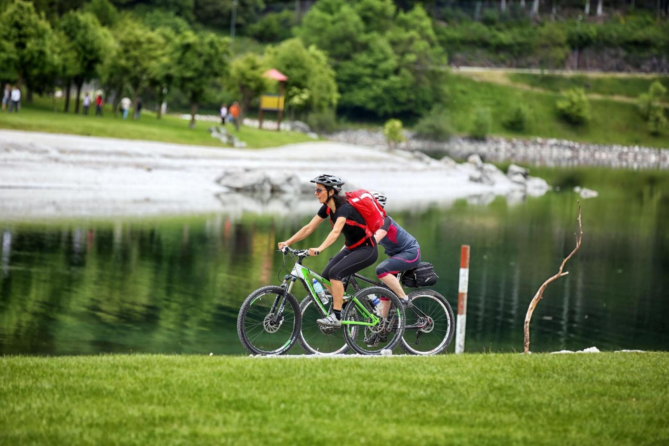 A person riding a bicycle on a grassy area near a body of water.