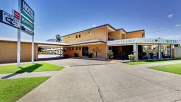A motel with a simple facade, a clear entrance, and a signboard indicating amenities like Wi-Fi and parking.