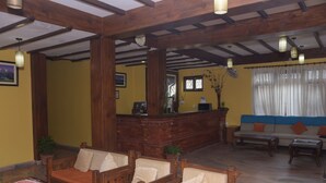 Un hall acogedor con muebles de madera, un mostrador de recepción y un sofá.