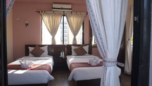 Habitación de hotel con dos camas, una mesita de noche, un aire acondicionado y una ventana con cortinas.
