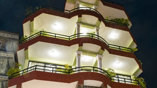 Un edificio de varios pisos con balcones, un cartel que dice