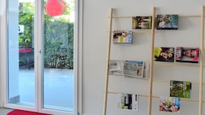 Una habitación con una puerta de cristal que da al exterior, un atril de madera para revistas y un felpudo rojo en la puerta.