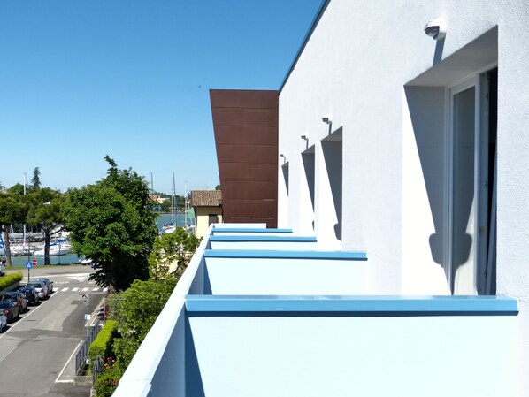 Un edificio moderno con fachada blanca y detalles azules, con vistas a una marina llena de barcos.