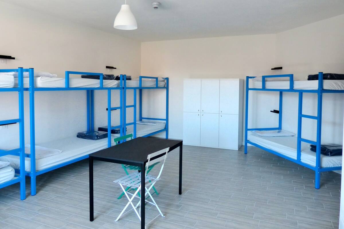 Um quarto de dormitório com beliches, uma mesa e uma cadeira.