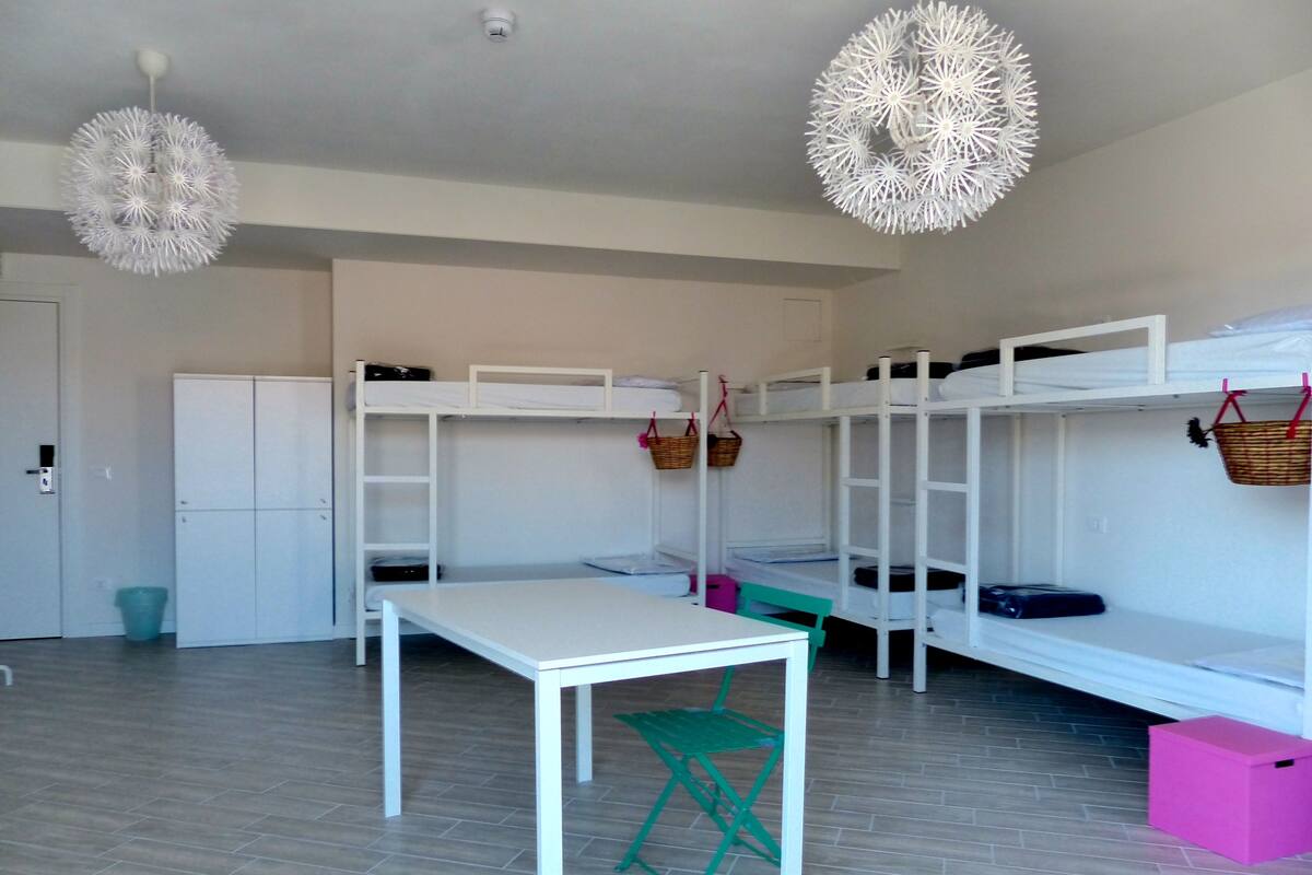 Quarto com beliches, uma mesa e uma cadeira.