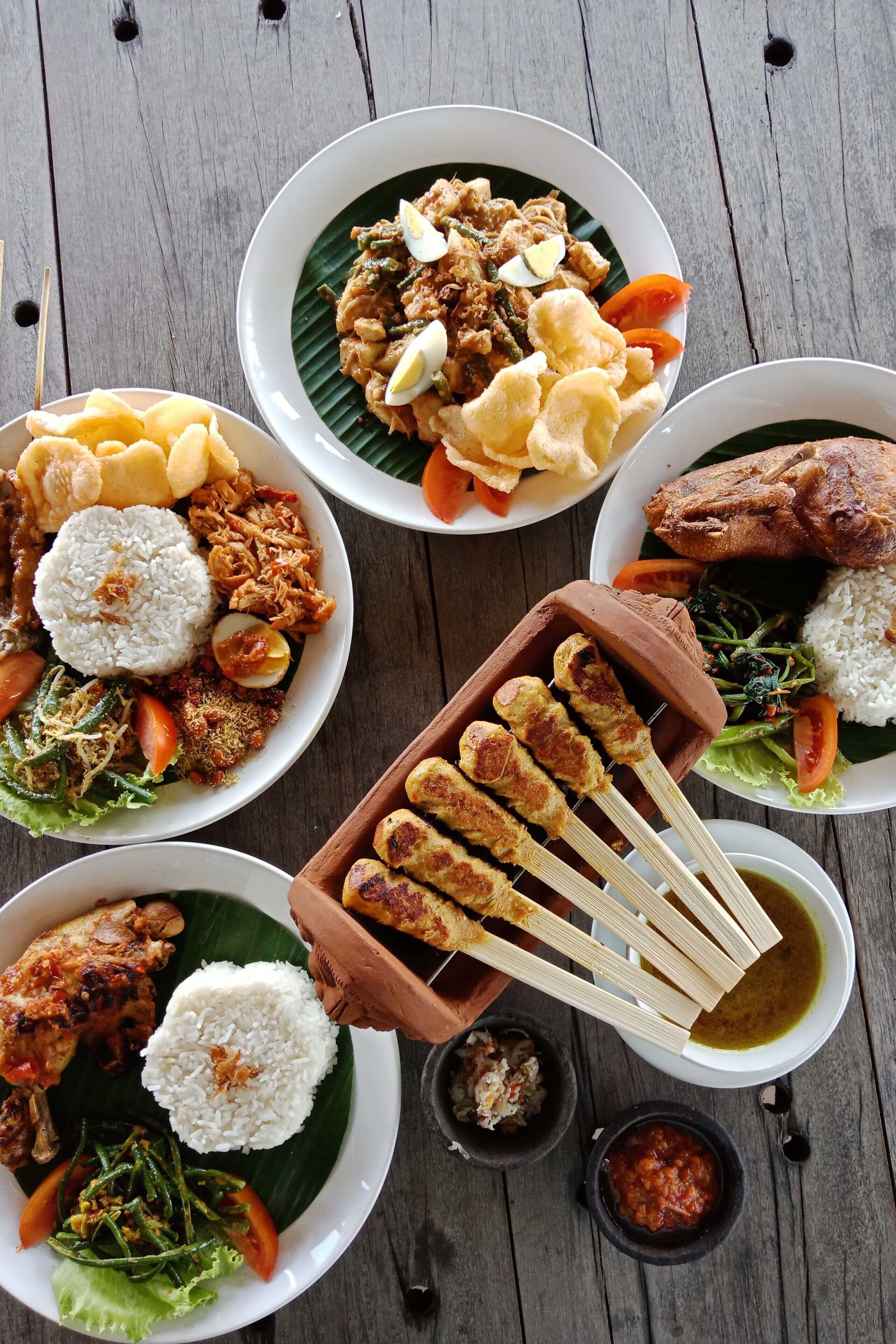 A variety of dishes including fried chicken, rice, and vegetables on a wooden table.