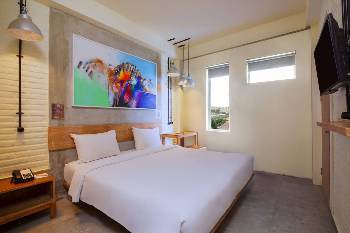 Un dormitorio moderno con una cama grande, un cuadro en la pared, un escritorio y un televisor.