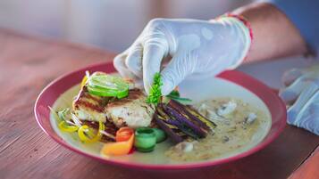 Una persona con guante blanco colocando una decoración en un plato de comida.