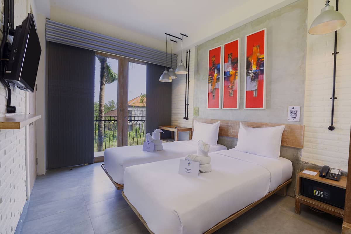 Habitación de hotel con dos camas, un balcón, televisión y obras de arte en la pared.