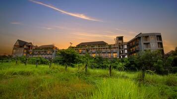 A multi-story hotel with balconies, surrounded by lush greenery.