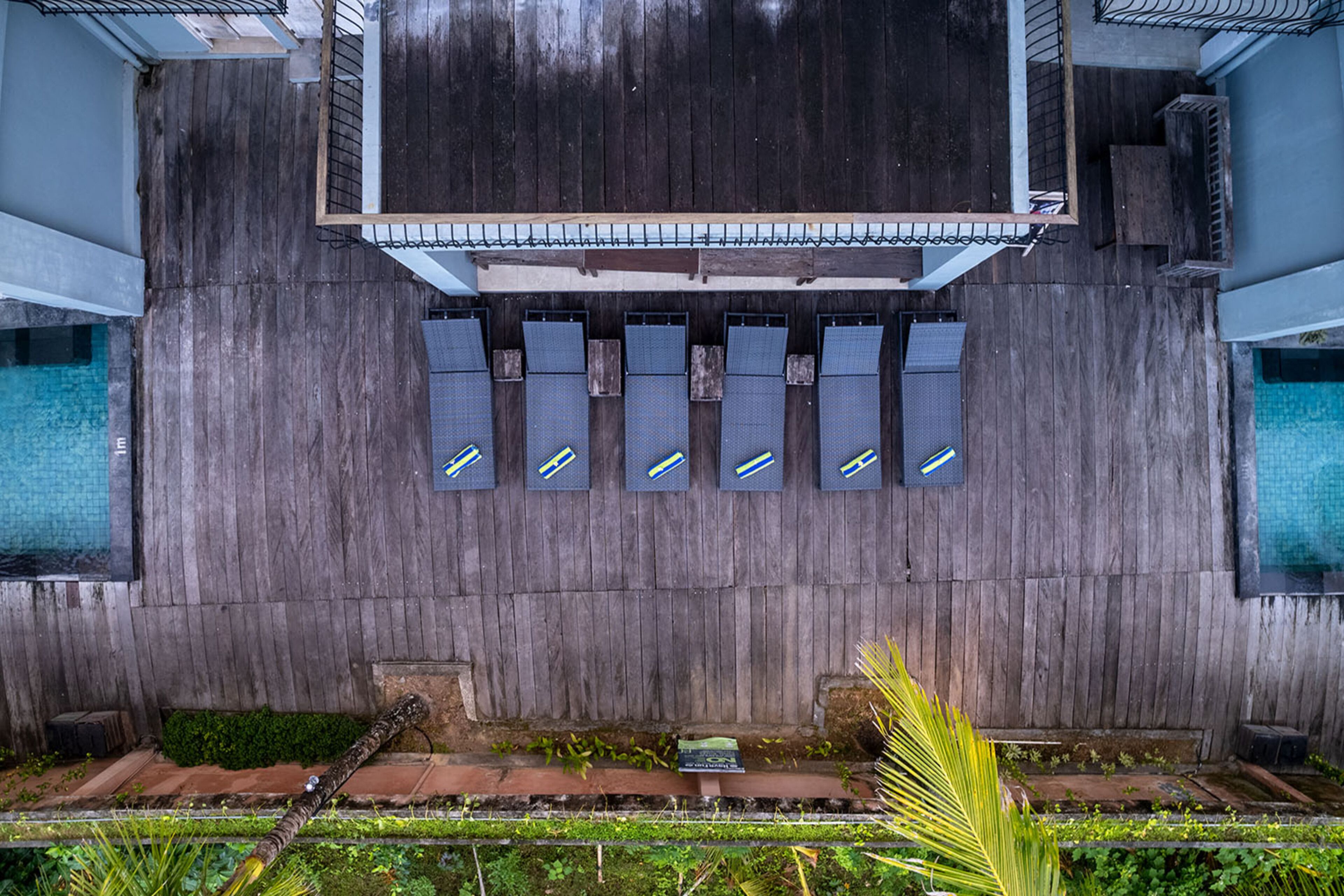 Una terraza en la azotea con piso de madera, piscina y varias ventanas.