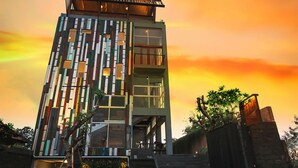 A modern building with a unique facade, balconies, and a small garden area. - FRii Bali Echo Beach (Canggu)