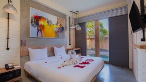 A hotel room with a large bed, a painting on the wall, a telephone on the nightstand, and a television mounted on the wall. - FRii Bali Echo Beach (Canggu)