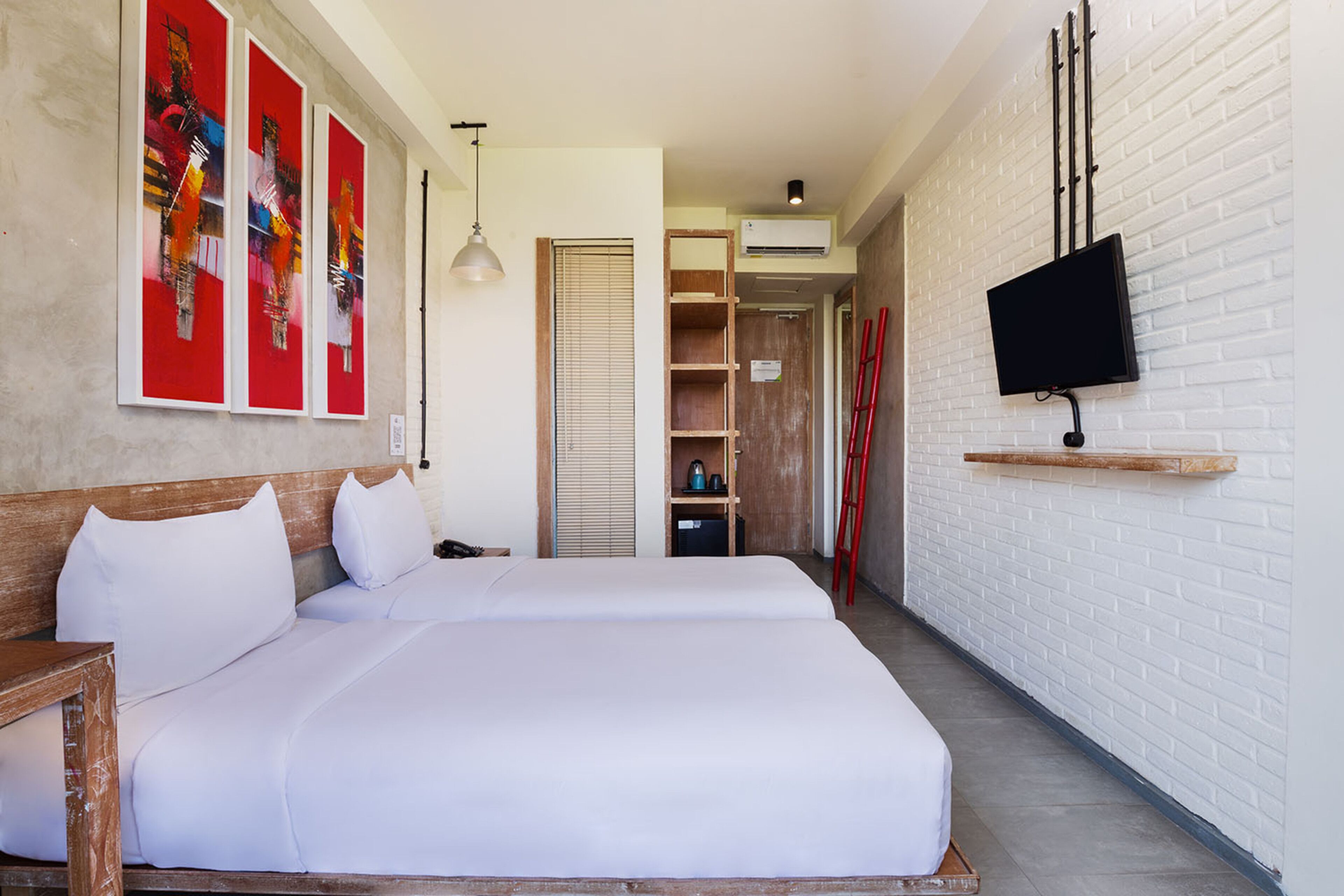 A hotel room with a large bed, a TV mounted on the wall, and artwork on the wall.