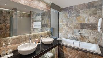 A modern bathroom with two sinks, a large mirror, and a bathtub.