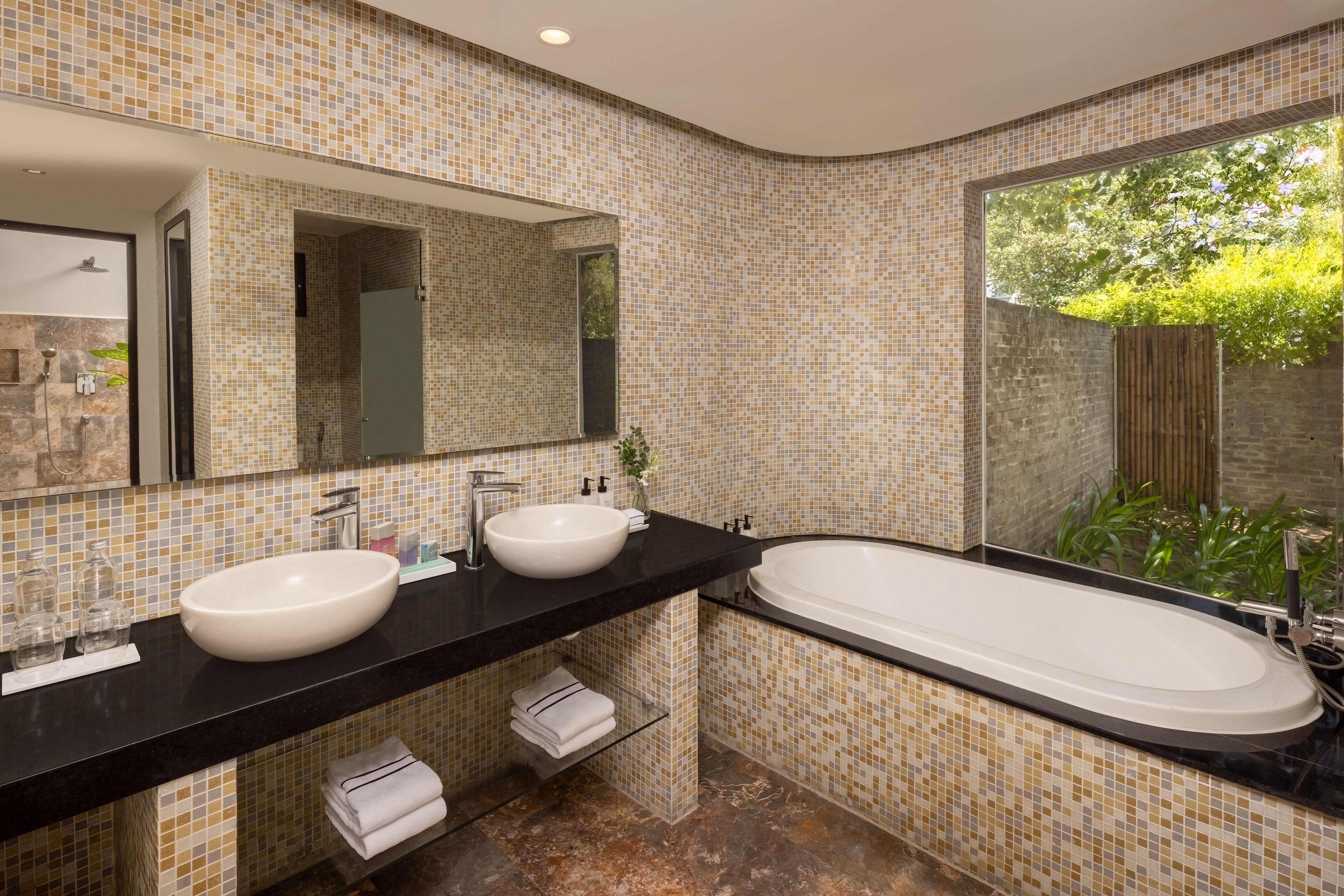 A modern bathroom with two sinks, a large bathtub, and a large mirror.