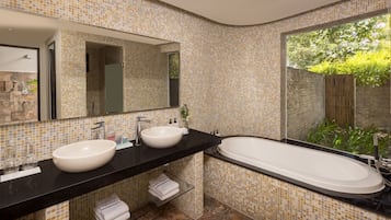A modern bathroom with two sinks, a large bathtub, and a large mirror.