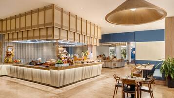 Un restaurante espacioso con una barra central, varias zonas de estar y una lámpara colgante grande.
