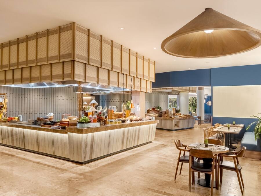 Un restaurante espacioso con una barra central, varias zonas de estar y una lámpara colgante grande.