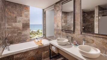 Un baño moderno con una bañera grande, dos lavamanos y vista al océano.