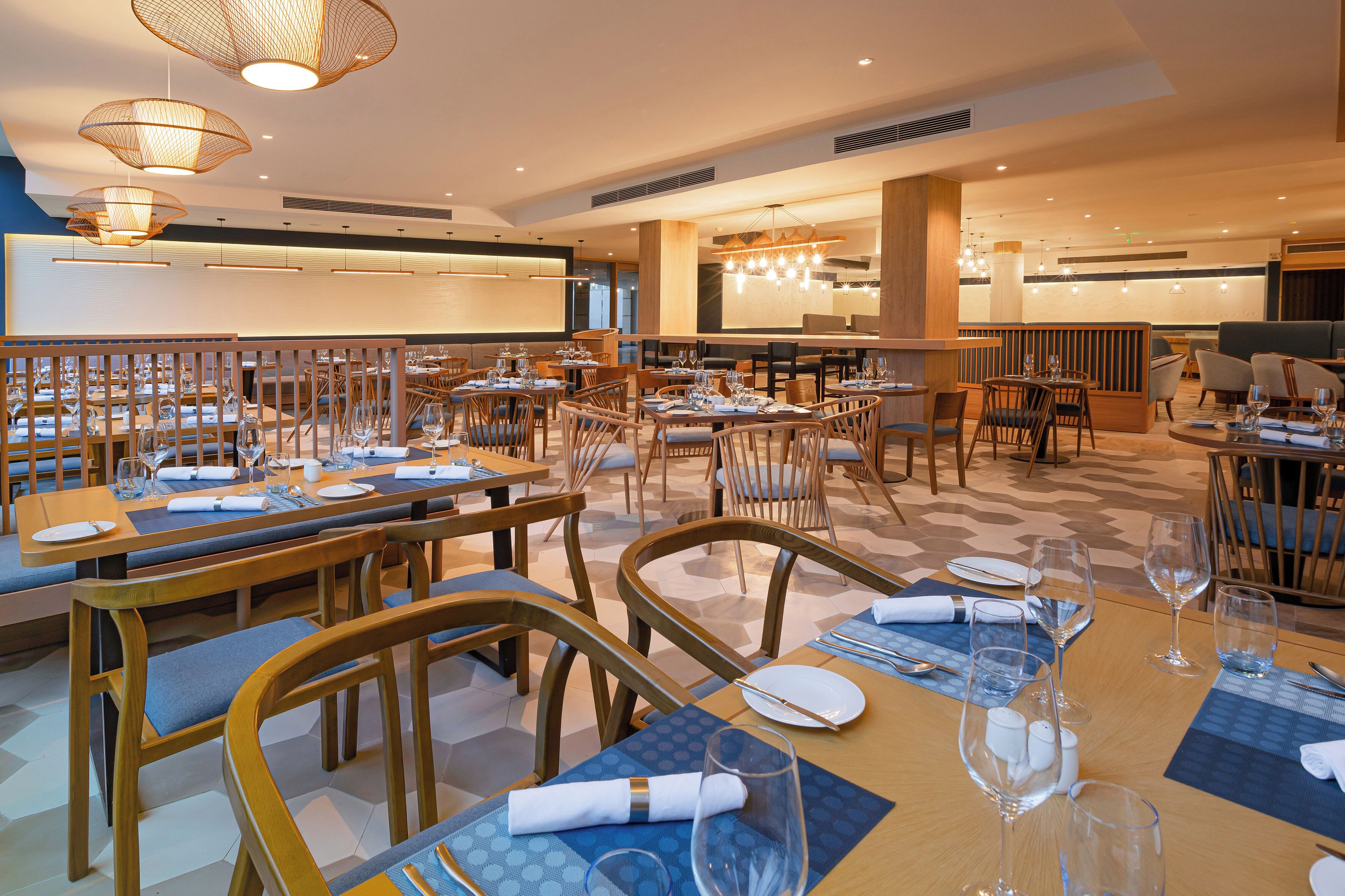A restaurant with multiple dining tables, chairs, and a bar area.