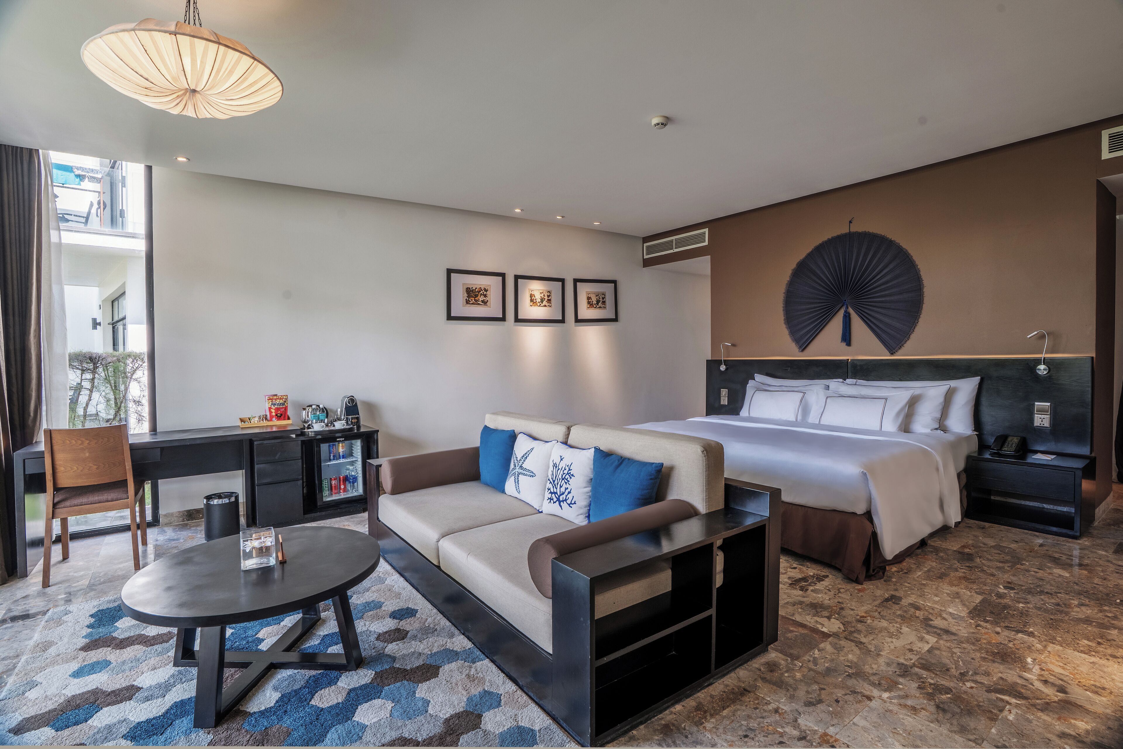 A hotel room with a bed, a sofa, a desk, and a dining table.