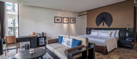 A hotel room with a bed, a sofa, a desk, and a dining table.
