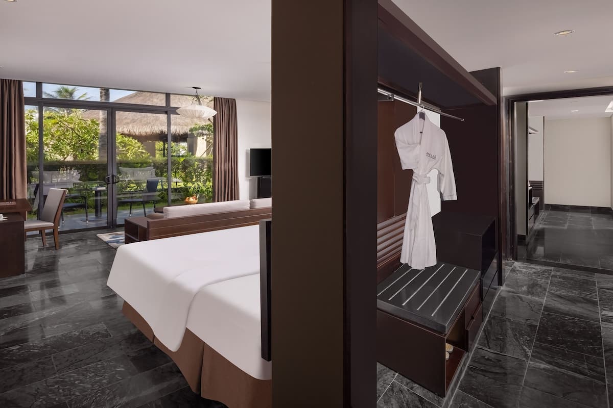 Ett modernt hotellrum med en stor säng, en sittgrupp med bord och stolar, en TV och utsikt över omgivningarna.