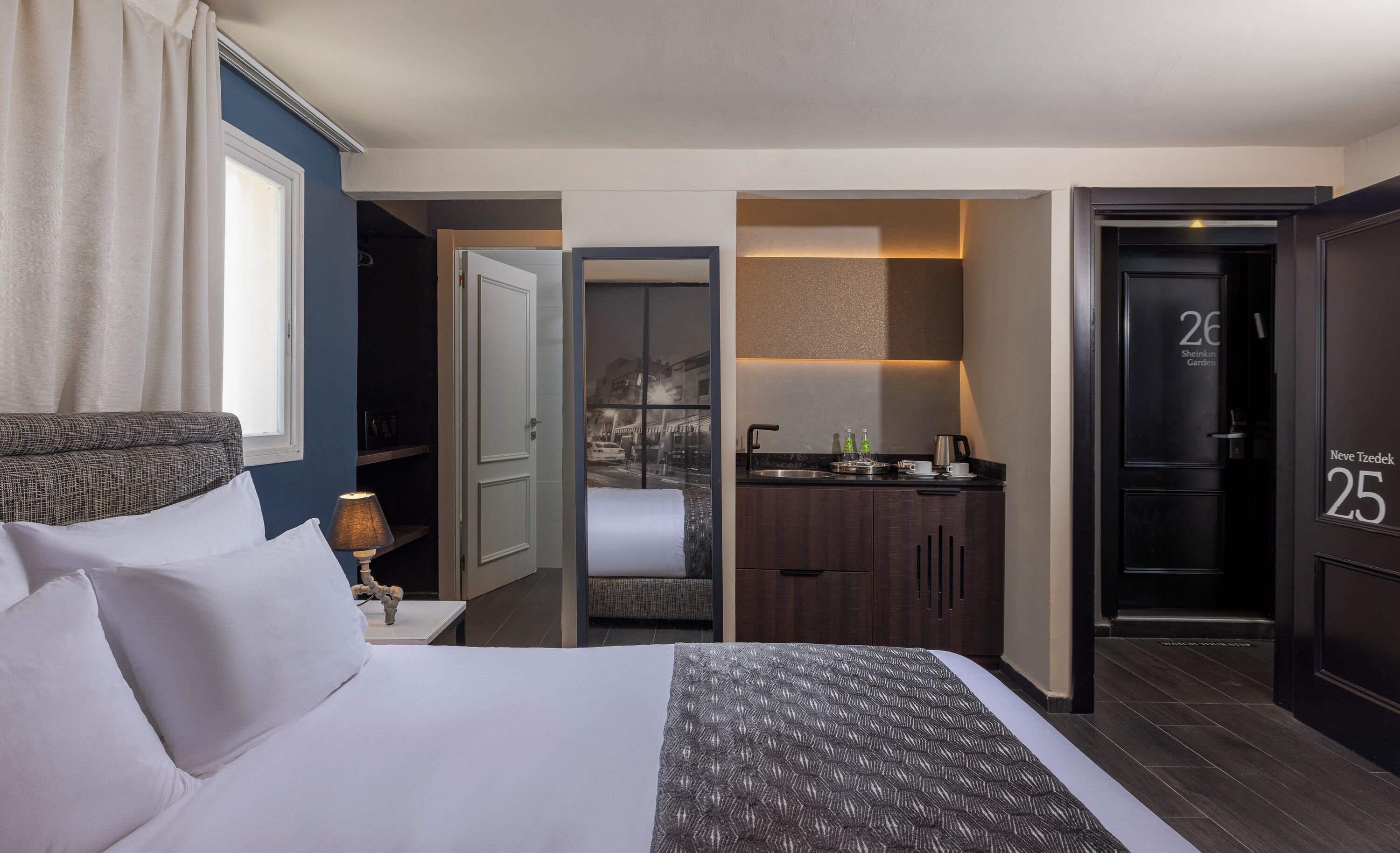 A hotel room with a bed, a desk, a bathroom, and a view of the city.
