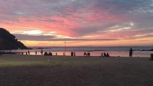 A beach at sunset with people walking and sitting on the sand. - Pousada Estevao (Cairu)