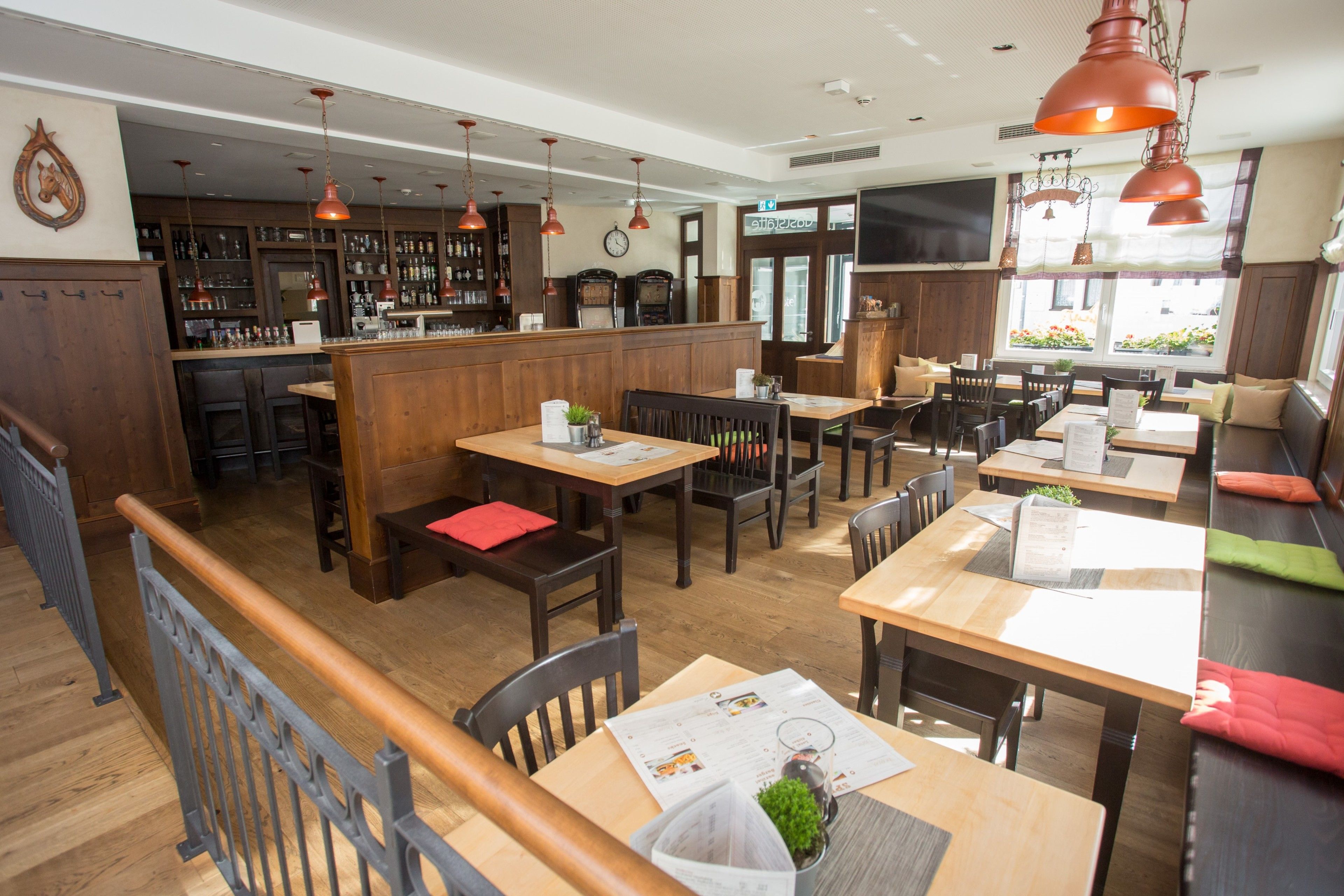 Ein Restaurant mit Holztischen und -stühlen, einer Bar und Blick auf die Straße.