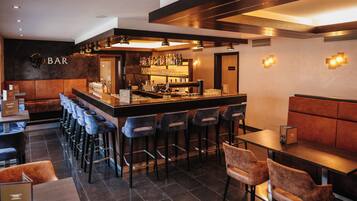 Eine Bar mit Theke, Hockern und Sitzgelegenheiten.