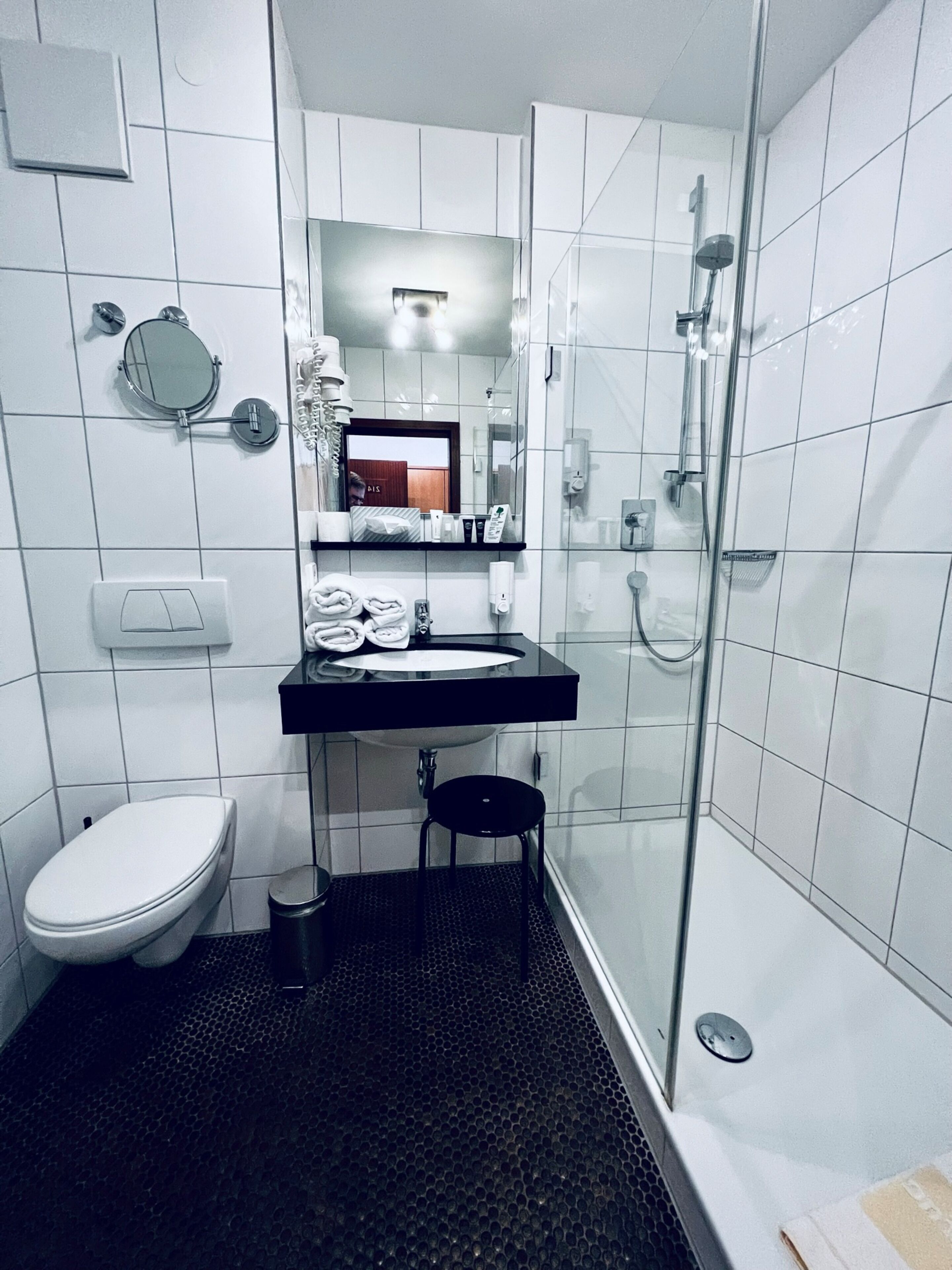 Un baño moderno con inodoro, lavamanos y cabina de ducha con mampara de vidrio.
