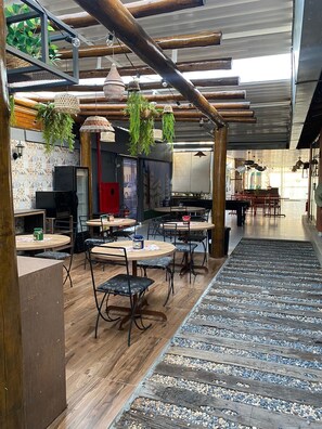 A restaurant interior with wooden tables, hanging plants, and a tiled wall. - Serra Negra Pousada Spa by Easy Hoteis (Guarapari)