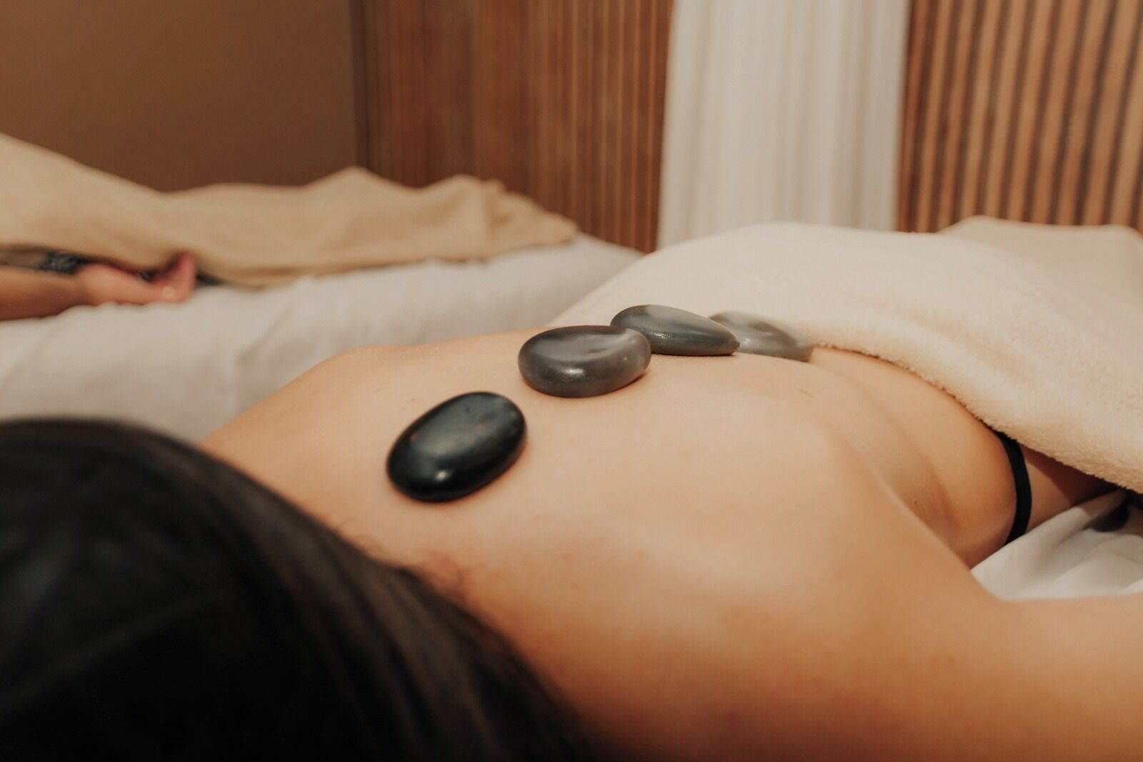 A person receiving a back massage with stones on their back.