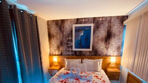 A hotel room with a large bed, two bedside tables, a wooden headboard, a wall-mounted picture, and a window with curtains. - Serra Negra Pousada Spa by Easy Hoteis (Guarapari)