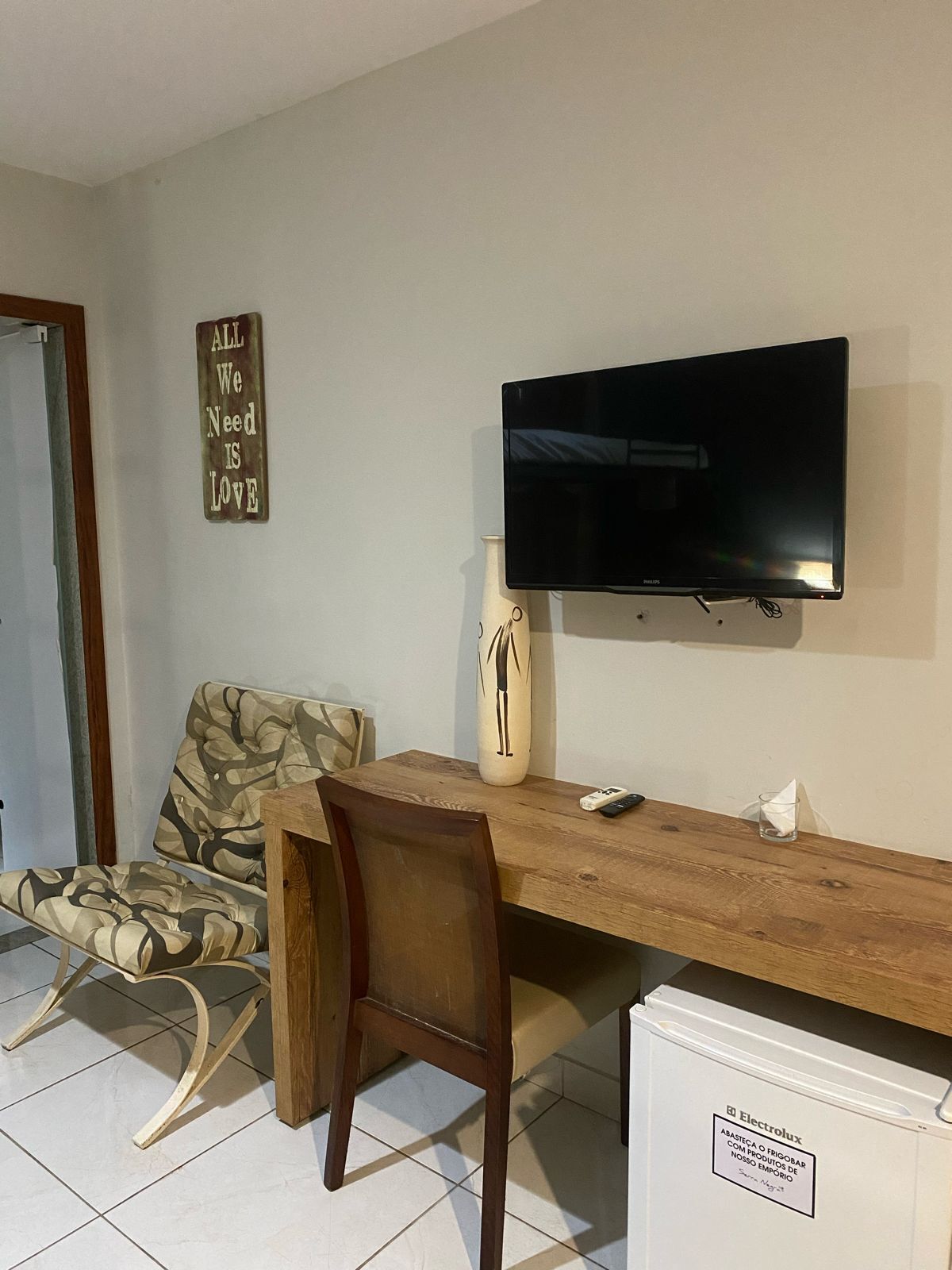 A living room with a wooden table, a sofa, a television, and a decorative vase.