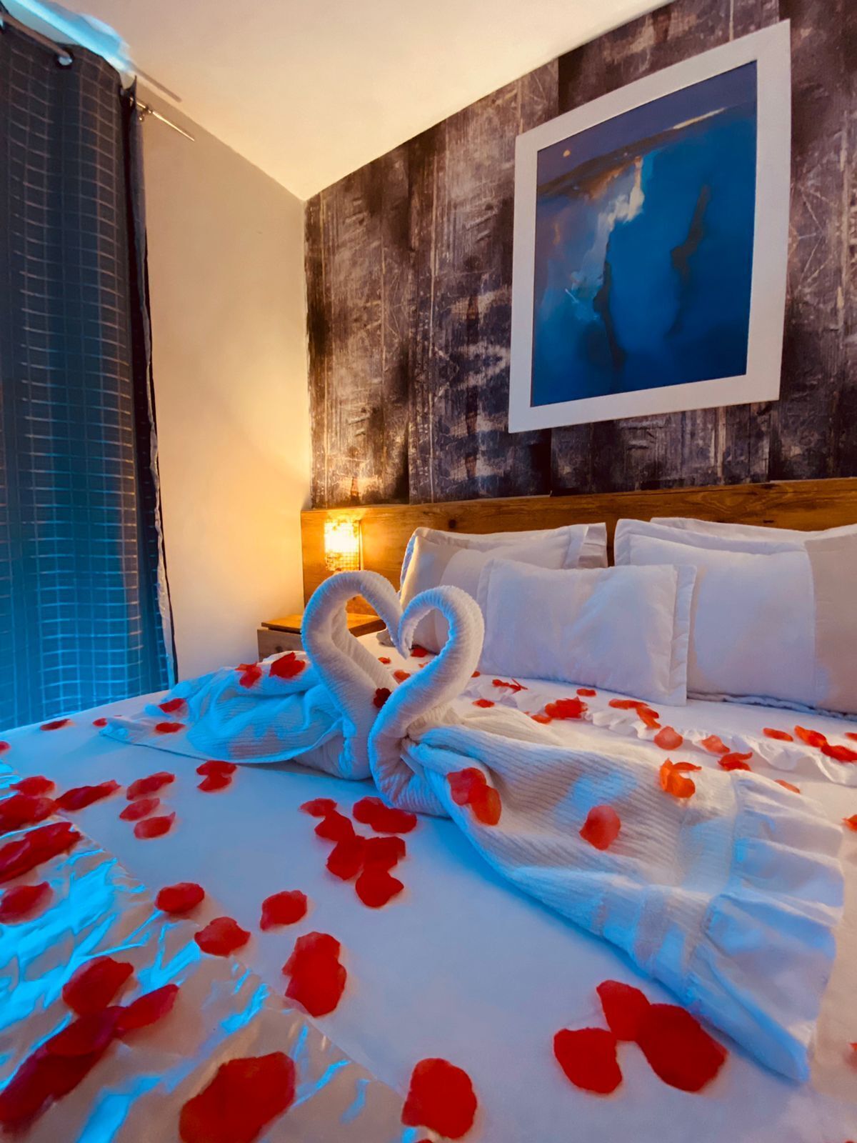 Une chambre d’hôtel avec un lit décoré de pétales de rose et un oreiller en forme de cygne.